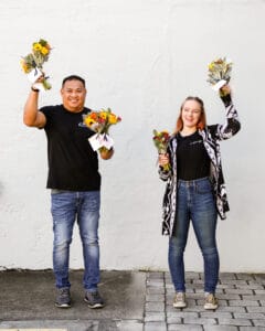 two in bloom works smiling and holding petal it forward bouquets