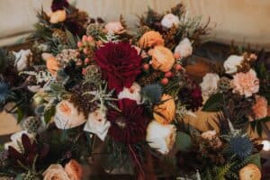 A fall flower arrangement with thistle, roses, dahlias, and greenery