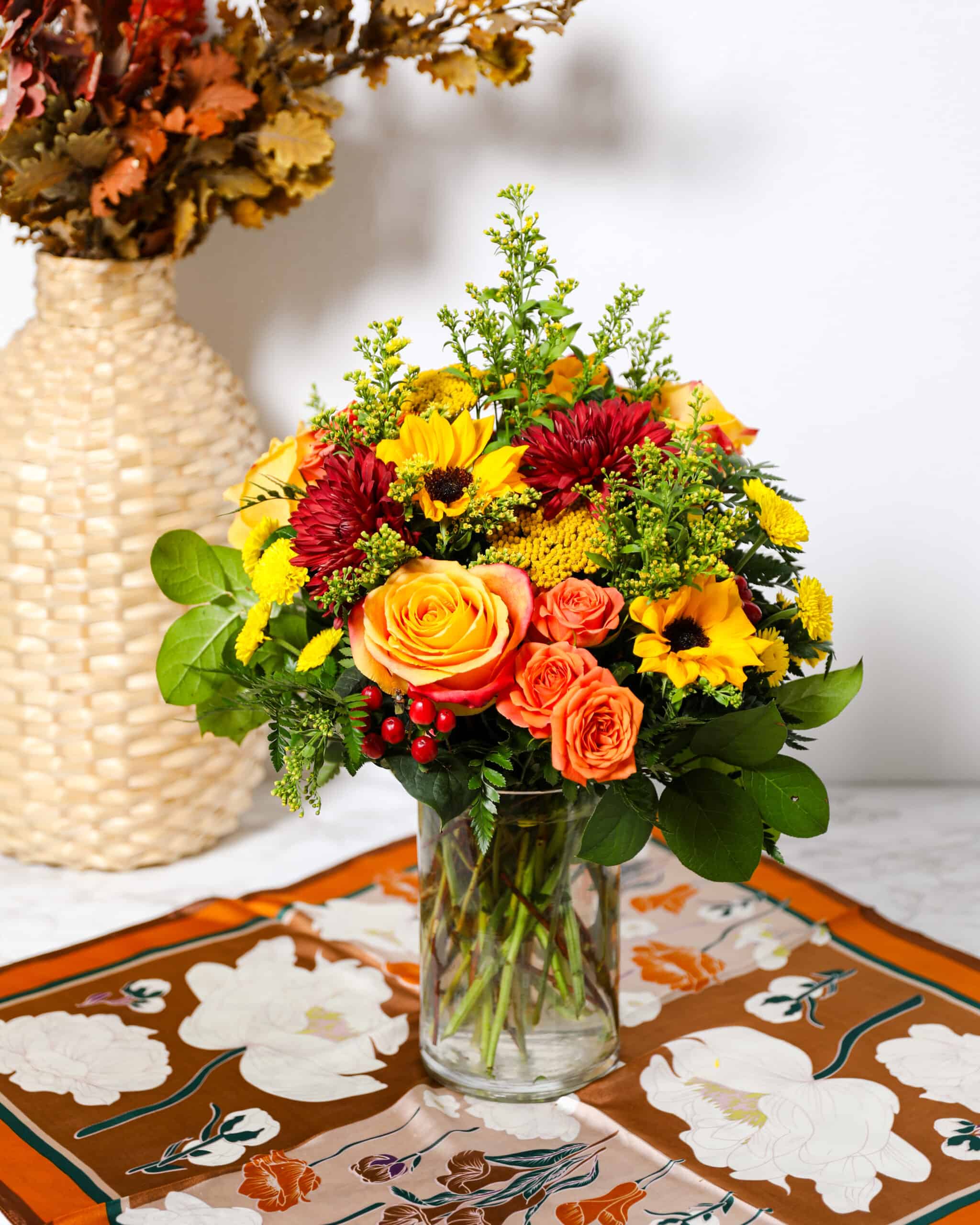 Falling Autumn - orange, yellow and red flowers and greenery in a glass vase