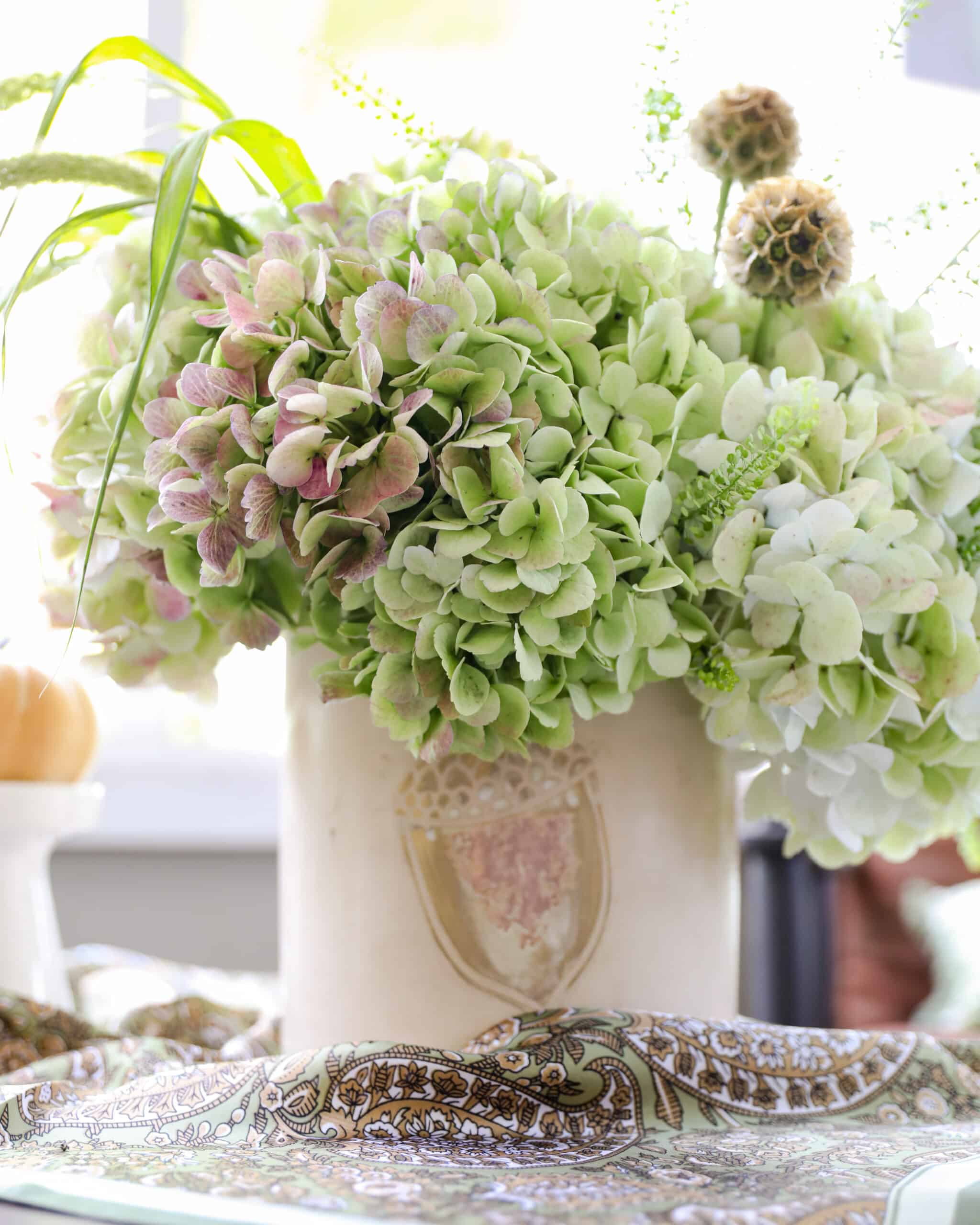 The Scenic Sage arrangement - green hydrangea and other light green and bronw florals in an acorn container