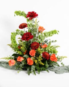 Custom flower arrangement with dark red cremones and orange roses made for the flower subscription service