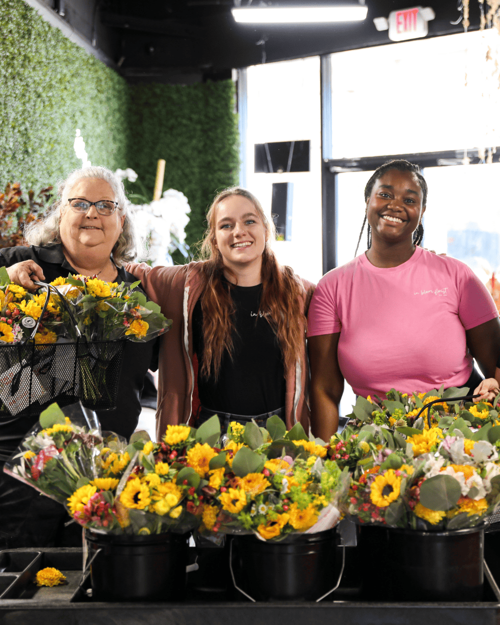 3 in bloom florist workers smiling in front of 100 bouquets to give away for free